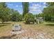 View of property with large grassy area, mature trees, and white home set in the background at 2205 Henley Rd, Lutz, FL 33558