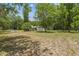 View of property with large grassy area, mature trees, and white home set in the background at 2205 Henley Rd, Lutz, FL 33558