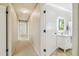 Hallway leading to a bathroom with a vanity and mirror, showcasing neutral walls and carpeted floors at 2205 Henley Rd, Lutz, FL 33558