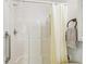 This all-white shower features a hand-held sprayer and grab bar for accessibility at 2205 Henley Rd, Lutz, FL 33558