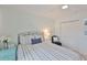 Bright bedroom with striped bedding, white curtains, and a ceiling fan at 230 Medallion Blvd # F, Madeira Beach, FL 33708