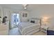 Bright bedroom with striped bedding, white curtains, and a ceiling fan at 230 Medallion Blvd # F, Madeira Beach, FL 33708