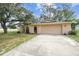Single-story home with a front yard, driveway, attached garage, and arched gate at 2410 Covington Ave, Spring Hill, FL 34608