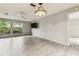 Spacious living room with wood-look floors, ceiling fan, and bright windows at 2410 Covington Ave, Spring Hill, FL 34608