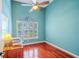Bedroom showcasing a window with plantation shutters, hardwood floors and light blue walls at 2417 Valrico Forest Dr, Valrico, FL 33594