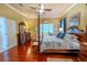 Spacious main bedroom featuring a four-poster bed, wood floors, and a decorative ceiling fan at 2417 Valrico Forest Dr, Valrico, FL 33594