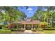 Exterior view of community clubhouse amidst mature trees, colorful shrubbery, and blue sky at 2690 Coral Landings Blvd # 217, Palm Harbor, FL 34684