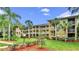 Exterior view of tan apartment homes with lush green landscaping and palm trees at 2690 Coral Landings Blvd # 217, Palm Harbor, FL 34684