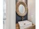 Stylish bathroom with a white vessel sink, wood framed round mirror, and modern fixtures at 3209 W Morrison Ave, Tampa, FL 33629