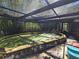 Enclosed pool with stone border and metal ladder steps, covered by a dark netting, with nature surrounding the enclosure at 32348 Marchmont Cir, Dade City, FL 33523