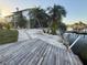 Wooden dock and waterfront with palm trees near the two story home at 3338 Fernleaf Dr, Hernando Beach, FL 34607