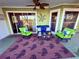 Inviting covered patio with comfortable seating, palm tree rug, and ceiling fan perfect for outdoor relaxation and entertaining at 3338 Fernleaf Dr, Hernando Beach, FL 34607
