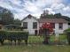 Lovely home featuring white siding with contrasting red trim, complemented by manicured greenery at 3405 E Diana St, Tampa, FL 33610