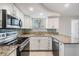 Bright kitchen with white cabinets, granite countertops, stainless steel appliances, and a view from the window at 3445 Pinehurst Dr, Holiday, FL 34691