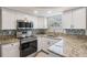 Bright kitchen featuring granite countertops, stainless steel appliances, stylish backsplash and white cabinetry at 3445 Pinehurst Dr, Holiday, FL 34691