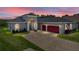 Beautiful single Gathering home with a brick driveway, three car garage and manicured lawn under a colorful sunset sky at 34652 Heavenly Ln, Dade City, FL 33525