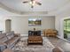 Comfortable living room with a large ceiling fan, media center, piano, and sliding glass doors at 34652 Heavenly Ln, Dade City, FL 33525