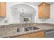 Close up of granite countertops, stainless steel sink, and modern backsplash in a bright home kitchen at 3512 Tealwood Cir, Palm Harbor, FL 34685