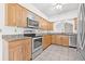 Bright kitchen with stainless steel appliances, wood cabinets, tiled floors, and granite countertops at 3512 Tealwood Cir, Palm Harbor, FL 34685