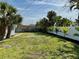 View of the large backyard with lush lawn, bordered by a white fence and palm trees at 440 89Th Ave, St Pete Beach, FL 33706