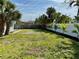 View of the large backyard with lush lawn, bordered by a white fence and palm trees at 440 89Th Ave, St Pete Beach, FL 33706