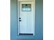 Close-up of a white front door with a decorative window pane and modern black hardware, offering a clean and inviting entrance at 440 89Th Ave, St Pete Beach, FL 33706