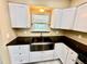 Farmhouse sink featuring sleek countertops and white cabinetry, with a window providing natural light at 440 89Th Ave, St Pete Beach, FL 33706