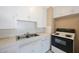 Compact kitchen featuring white cabinets, a stainless steel sink, and a black electric range at 513 88Th N Ave, St Petersburg, FL 33702