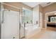 Main bathroom featuring a soaking tub, walk-in shower, glass block window, and doorway into main bedroom at 5704 Eaglemount Cir, Lithia, FL 33547