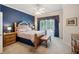 Comfortable main bedroom featuring a blue accent wall, neutral carpet, ceiling fan, and sliding doors with outdoor view at 5704 Eaglemount Cir, Lithia, FL 33547