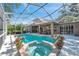 Beautiful screened-in pool with a hot tub, surrounded by lush landscaping at 5704 Eaglemount Cir, Lithia, FL 33547