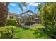A view of the screened in patio area with tropical trees and lush green grass at 703 Monte Cristo Blvd, Tierra Verde, FL 33715