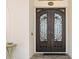 Elegant front entrance featuring decorative wrought iron double doors, textured stucco, and brick paved porch at 703 Monte Cristo Blvd, Tierra Verde, FL 33715