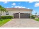 A two car garage has a brick driveway and manicured bushes surrounding it at 703 Monte Cristo Blvd, Tierra Verde, FL 33715