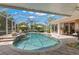 Inviting screened-in pool area with comfortable seating and view of the tropical plants and landscaping at 703 Monte Cristo Blvd, Tierra Verde, FL 33715