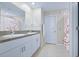 Bright bathroom featuring double sinks with granite counters and a shower with a floral curtain at 7170 Samuel Ivy Dr, Tampa, FL 33619