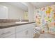 Bright bathroom featuring a white vanity with granite countertop and colorful shower curtain at 7170 Samuel Ivy Dr, Tampa, FL 33619