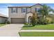 Two-story home featuring a two-car garage, manicured lawn, and tropical landscaping at 7170 Samuel Ivy Dr, Tampa, FL 33619