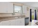 Kitchen sink area with white cabinets and granite counters, plenty of natural light from window at 7170 Samuel Ivy Dr, Tampa, FL 33619