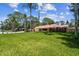 Ranch home with green lawn, tropical trees, and an American flag waving under a blue sky at 7507 Beasley Rd, Tampa, FL 33615