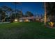 Single-story home with sprawling front yard, mature trees and tropical landscaping at dusk at 7507 Beasley Rd, Tampa, FL 33615
