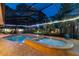 Inviting screened-in pool and spa area with enchanting backyard lighting and a lush, green landscape at 7507 Beasley Rd, Tampa, FL 33615
