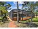 An in-ground screened pool with brick surround, surrounded by lush landscaping at 7507 Beasley Rd, Tampa, FL 33615