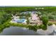 Aerial view of the clubhouse, pool, and tennis courts nestled by a lake with lush surroundings and mature trees at 9481 Highland Oak Dr # 1511, Tampa, FL 33647