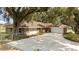 Brick home with a large driveway surrounded by lush, mature trees at 9542 Wallien Dr, Brooksville, FL 34601