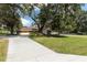 Stunning single story home exterior with brick and wood siding, lush greenery, and an expansive driveway at 9542 Wallien Dr, Brooksville, FL 34601