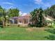 Expansive backyard with a screened-in lanai, tropical foliage, and well-manicured lawn at 10504 Echo Lake Dr, Odessa, FL 33556