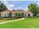 Elegant home with a manicured lawn, lush landscaping, and a brick pathway at 10504 Echo Lake Dr, Odessa, FL 33556