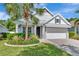 Charming home showcasing lush landscaping, a well-manicured lawn, and a gray metal roof at 11510 Quiet Forest Dr, Tampa, FL 33635