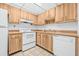 Efficient kitchen features wood cabinetry, white appliances, and tile flooring at 11816 Raintree Lake Ln # B, Tampa, FL 33617